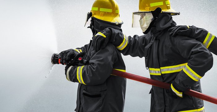 Feuerwehrmänner im Einsatz. Sie tragen Feuerschutzkleidung aus Hochleistungsgarnen. Die Hochleistungsgarne werden auf SAHM Spulmaschinen aufgespult.