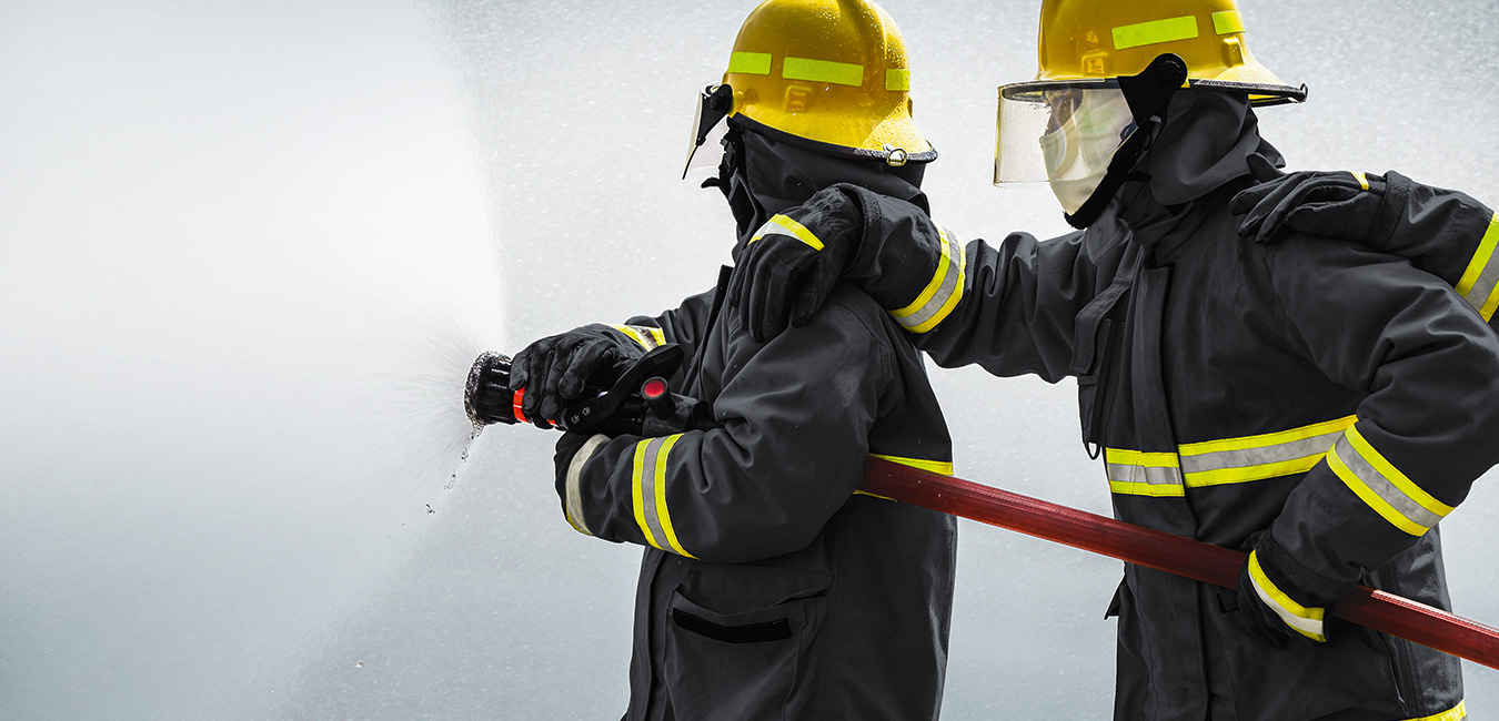 Feuerwehrmänner bei der Arbeit. Sie tragen feuerfeste Kleidung aus Hochleistungsfasern.