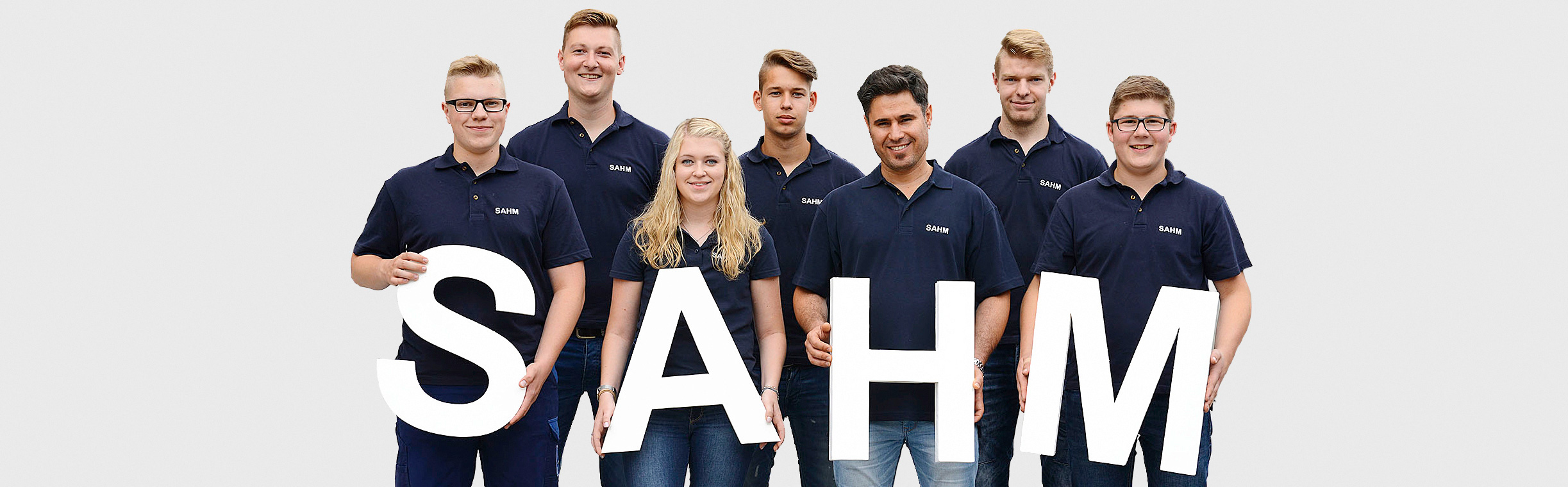 SAHM Auszubildende Sieben SAHM Auszubildende, die vier Buchstaben "SAHM" vor sich halten